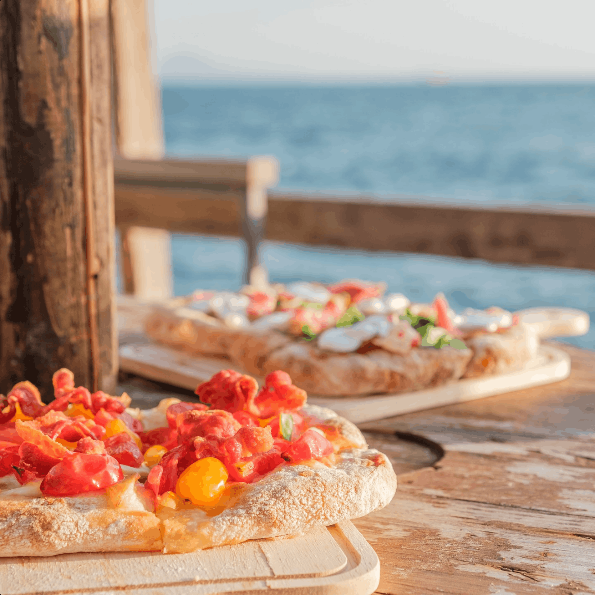 Pinse e taglieri serviti al tavolo del Noa, con il mare sullo sfondo