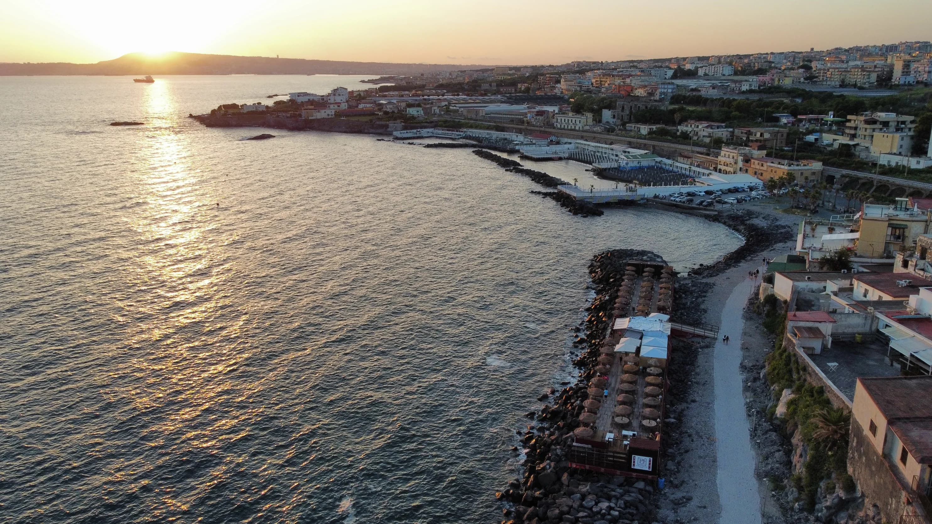 Noa Beach visto dall'alto al tramonto, deck in legno sul mare di Torre del Greco